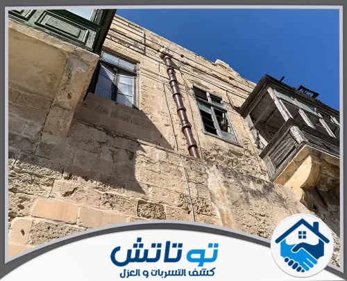 هدم وترميم مباني في العين 0565603382 شركة توتاتش تناغم الحجر والسقالات مشهد لمبنى حديث في اللمسات النهائية للتشطيب الخارجي تحت ضوء الشمس.