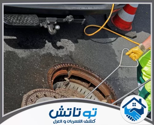 سيارة فتح المجاري المسدودة في راس الخيمة 0565603382 شركة توتاتش فني يستخدم أداة حديدية لفتح غطاء صرف صحي ثقيل في الشارع لبدء عمليات الفحص والتنظيف